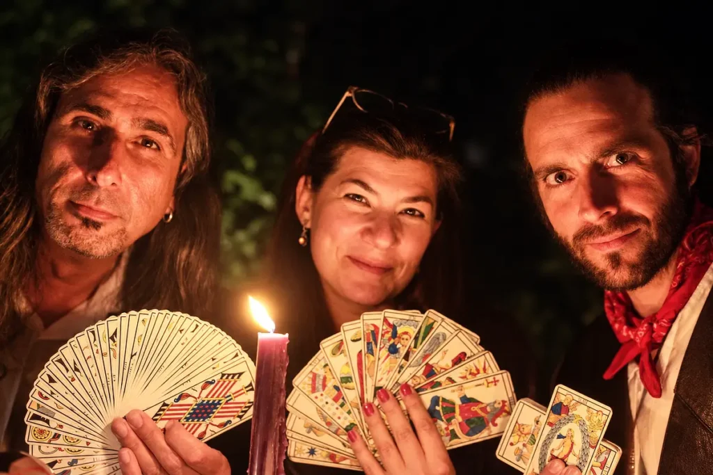 Tres tarotistas mostrando cartas junto a una vela durante un evento