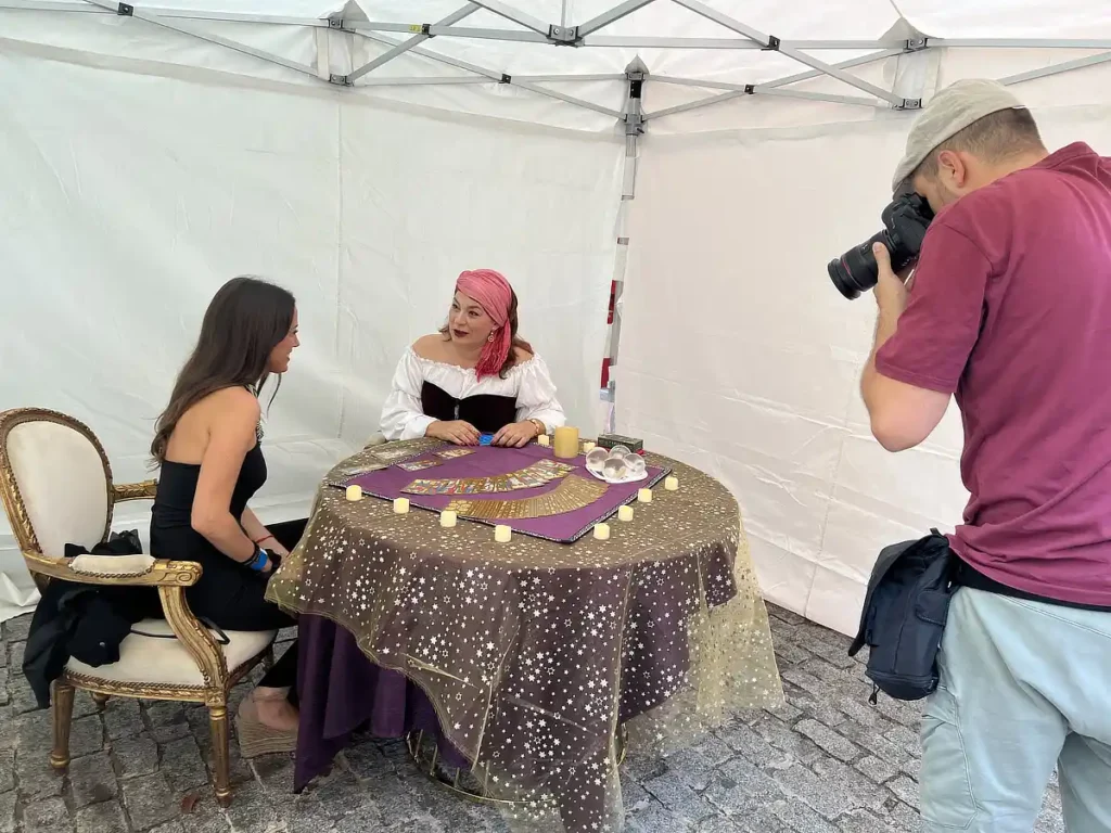 Tarotista realizando una lectura a una invitada mientras un fotógrafo toma imágenes del evento